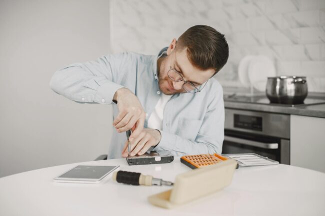 man sitting at a table and tinkering using a screwdriver