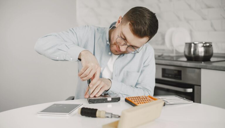 man sitting at a table and tinkering using a screwdriver