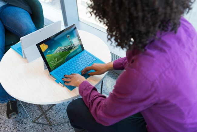 person using blue laptop sitting beside table