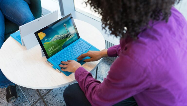 person using blue laptop sitting beside table