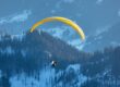 paraglider soaring over snowy dolomites in winter
