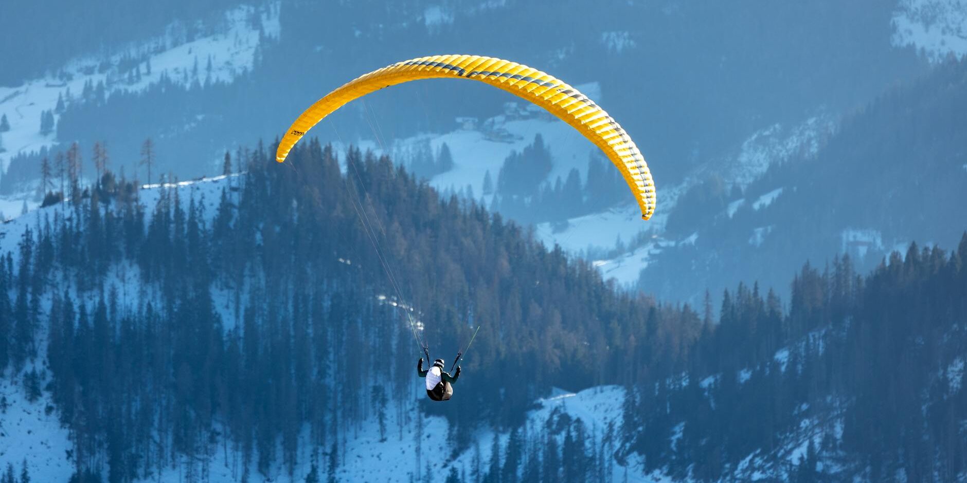 paraglider soaring over snowy dolomites in winter