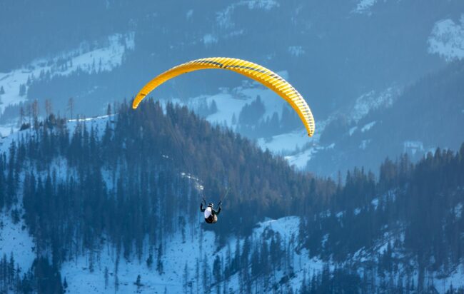 paraglider soaring over snowy dolomites in winter
