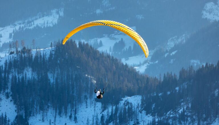 paraglider soaring over snowy dolomites in winter