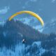 paraglider soaring over snowy dolomites in winter