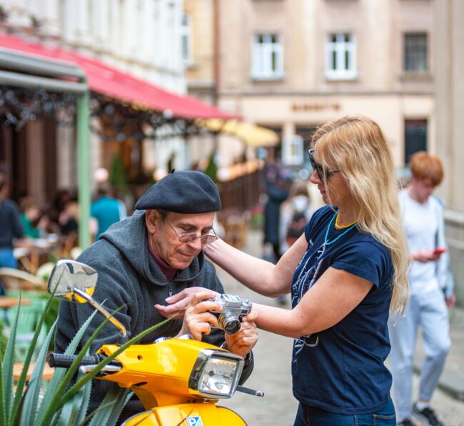 man on scooter and blonde woman looking at camera