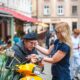 man on scooter and blonde woman looking at camera