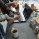 people standing beside man using laptop on gray table with silicon forms