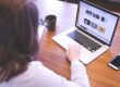 woman swiping touchpad on macbook pro on table near smartphone and mug