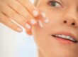woman applying moisturizer to face close up