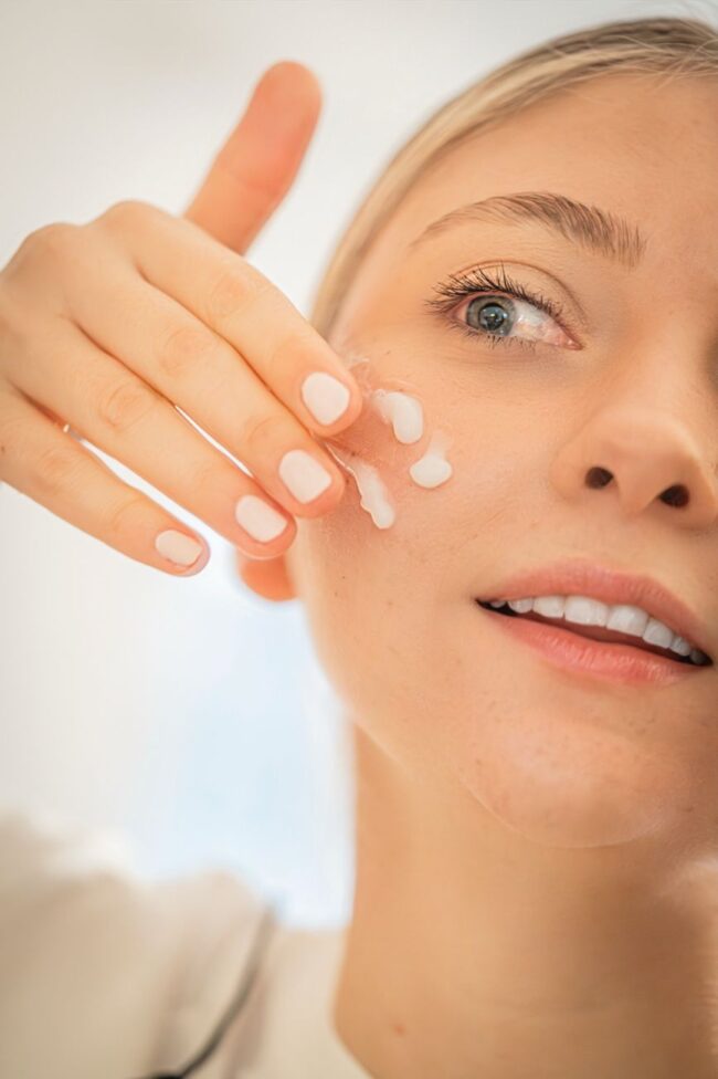 woman applying moisturizer to face close up