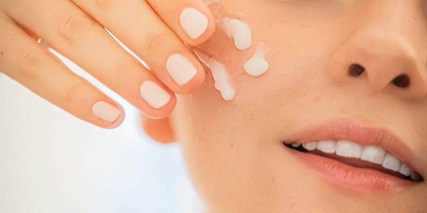 woman applying moisturizer to face close up