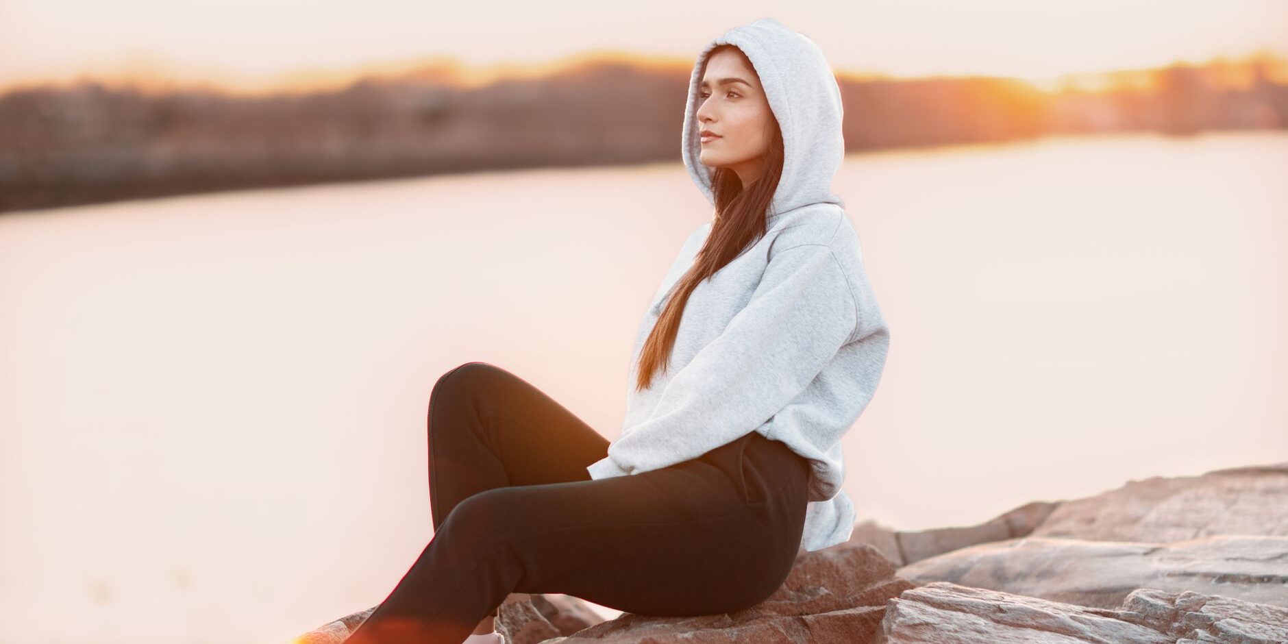 woman in gray hoodie sitting on rock