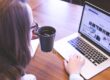 person holding mug while using laptop