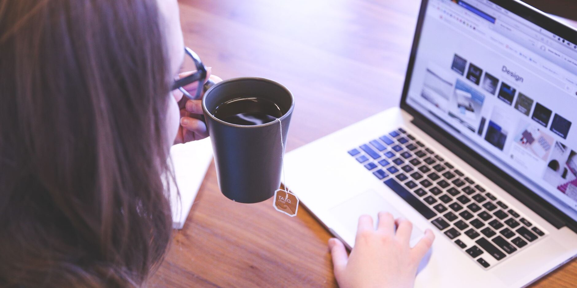 person holding mug while using laptop