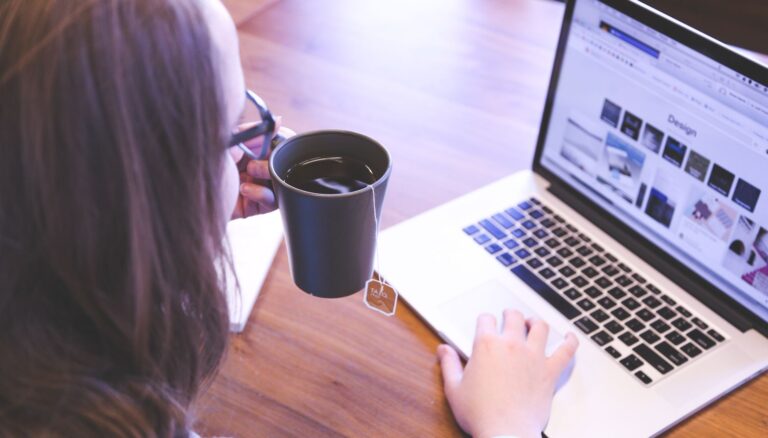 person holding mug while using laptop