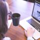 person holding mug while using laptop